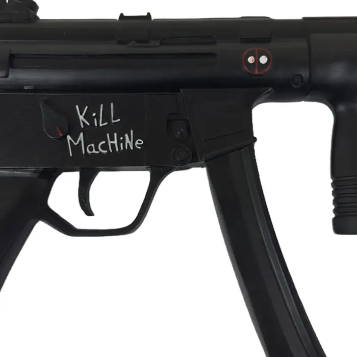 Pistola de Deadpool, primer plano de la inscripción «Kill Machine» y el logotipo de Deadpool